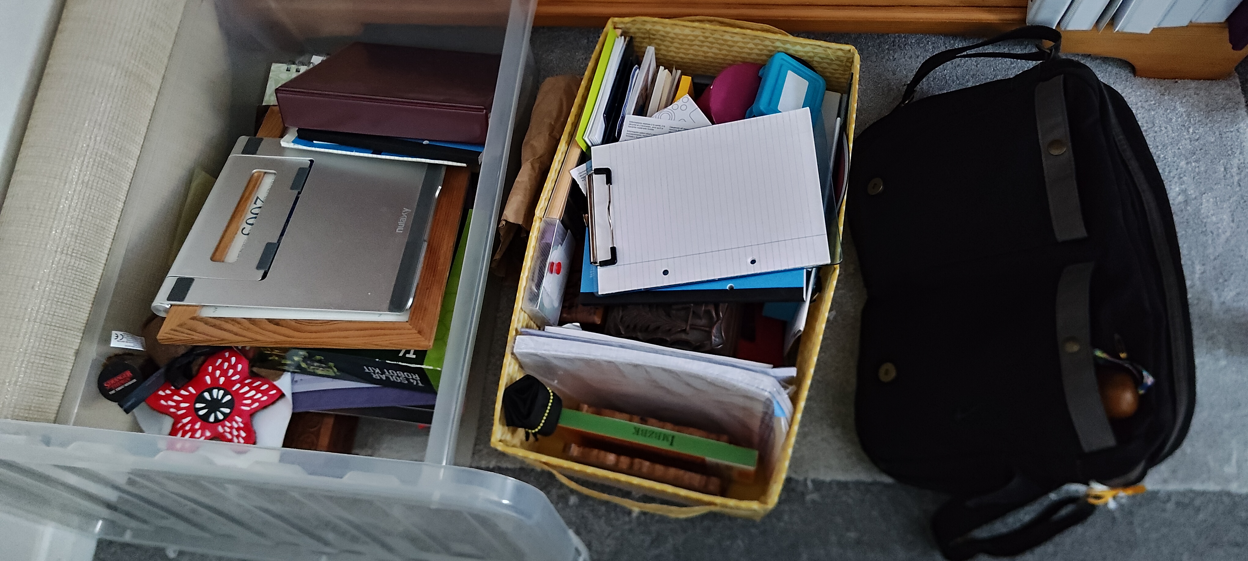 some of the STUFF A photograph of some of the STUFF - a clear plastic crate containing misc objects such as a cuddly demagorgon from Stranger Things, a folding laptop stand, and a robot-building kit; a yellow storage box filled with stationary; and a black messenger bag that serves as my work bag.